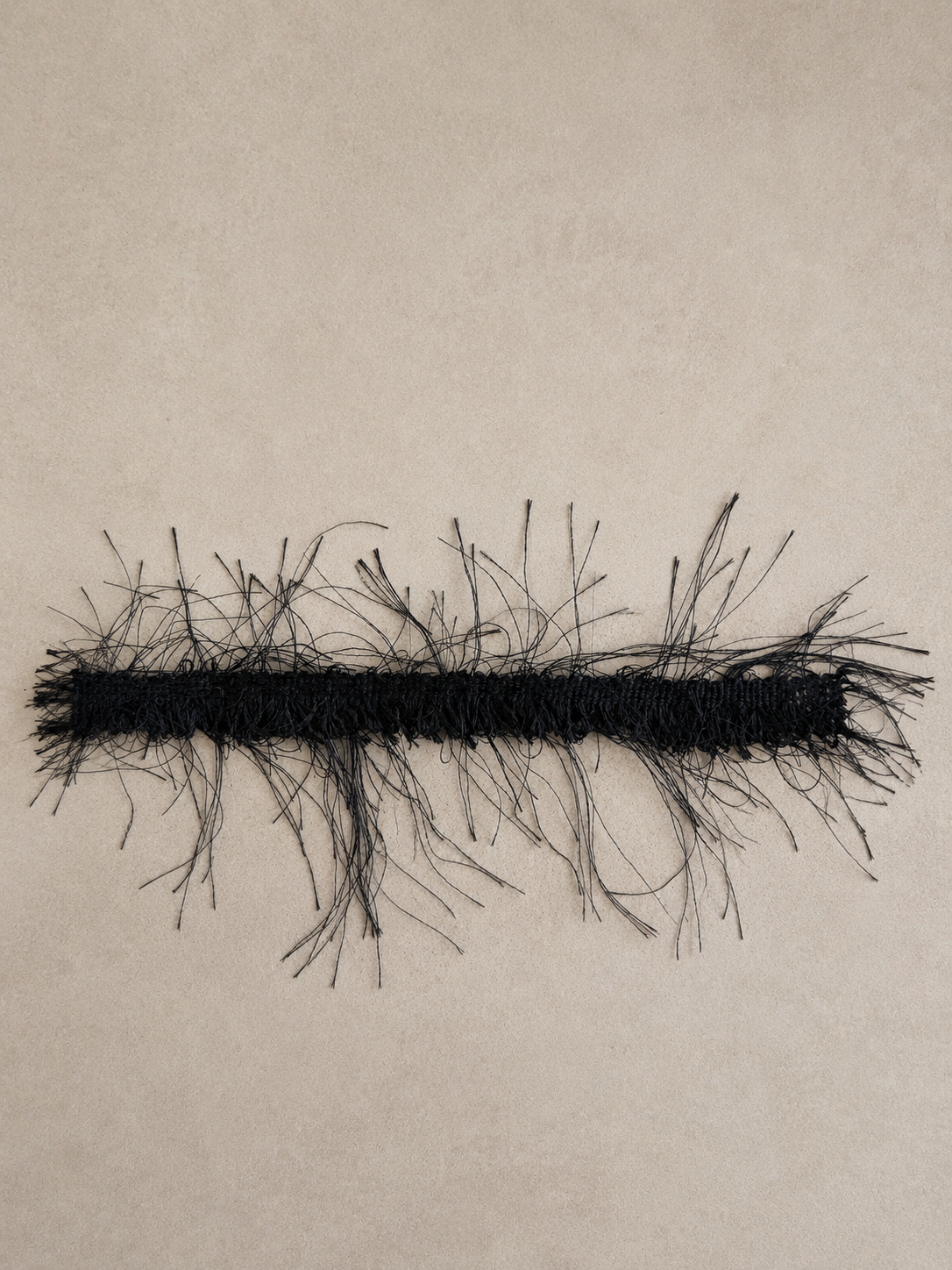 Black eyelash fringe tissue box cover with delicate wispy fibers and dramatic texture, designed as a sculptural decorative accent for luxury interiors.