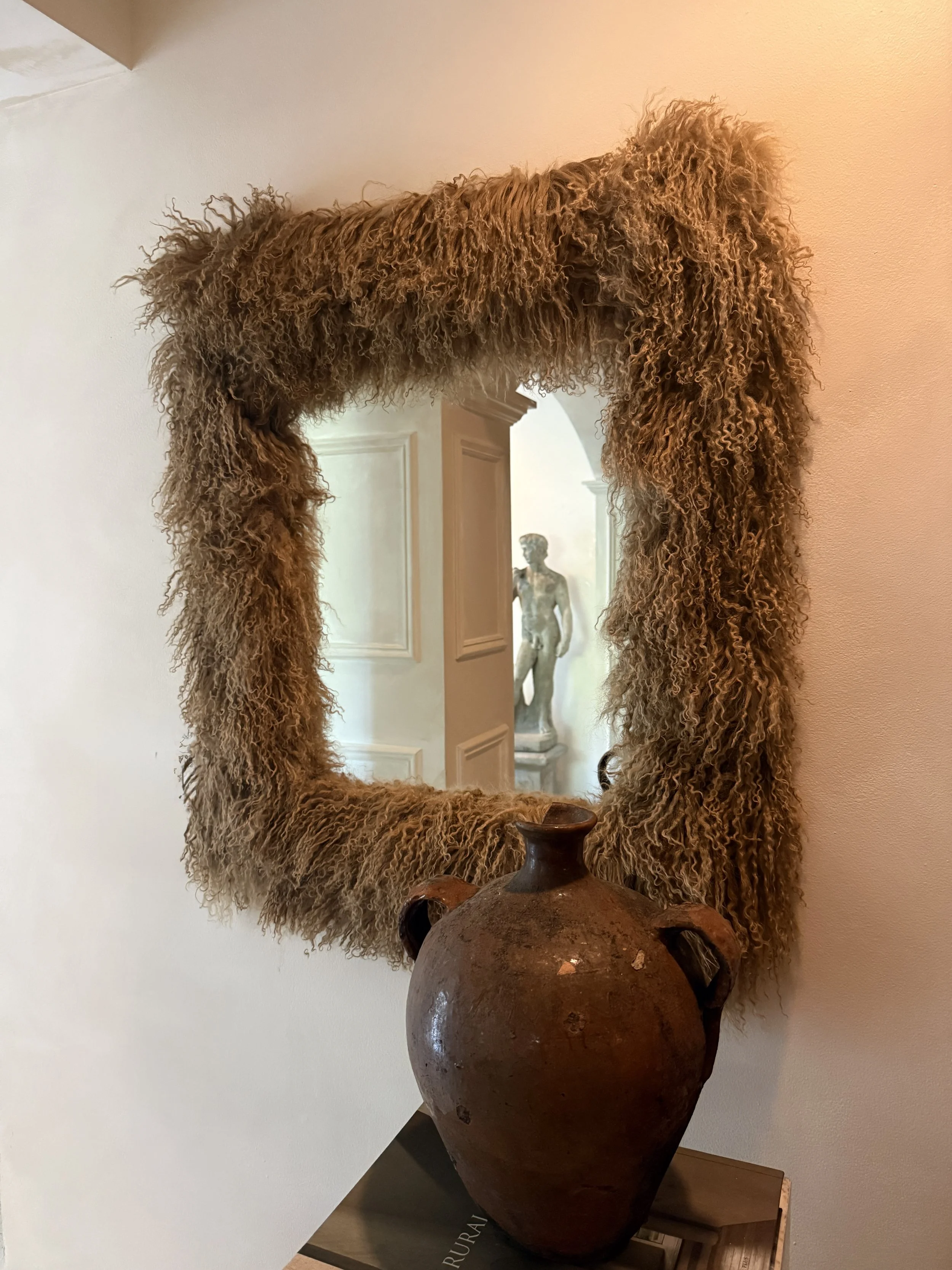 Mongolian lamb sheepskin mirror in Miso — a warm, textural beige tone styled against a plaster wall with soft natural light.