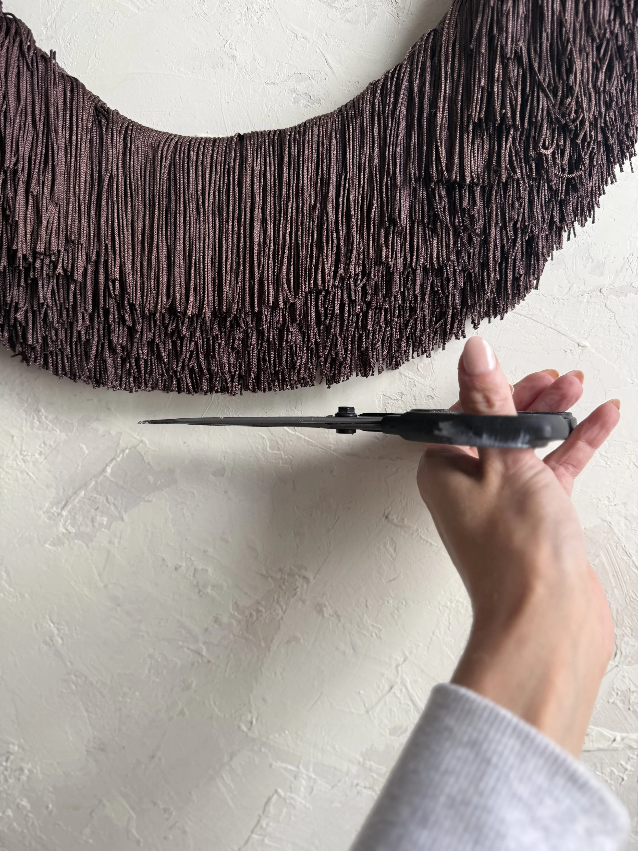 Dark fringe-wrapped oval mirror.