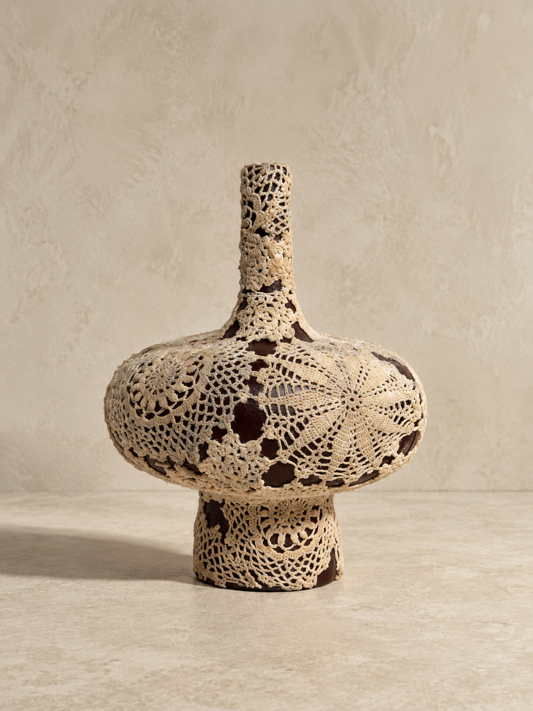 Veil Vessel by Amber Renee Hansen, a deep brown ceramic vessel wrapped in warm ivory vintage hand-crocheted lace.