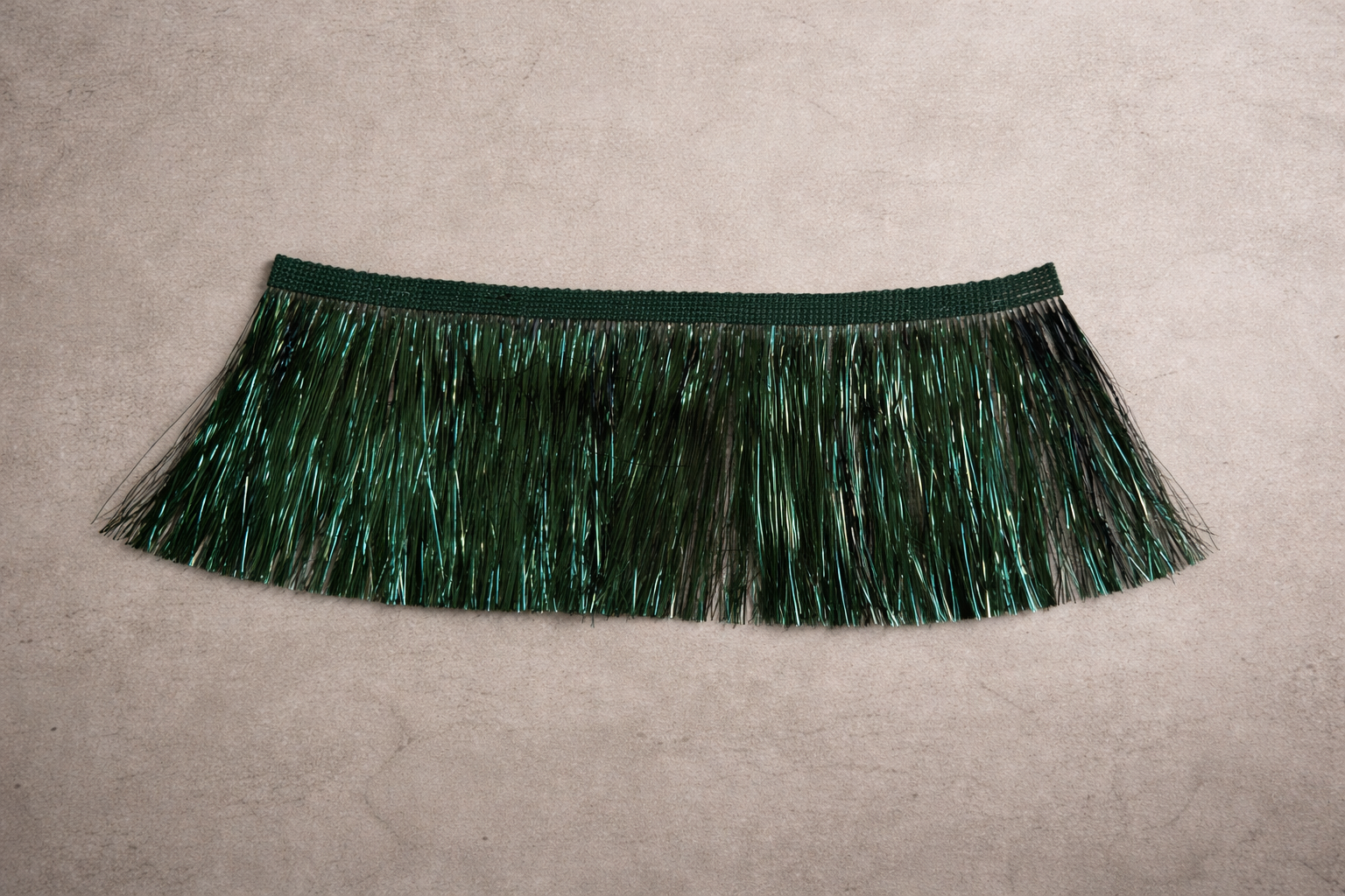 Emerald static fringe tissue box cover with dimensional tinsel strands displayed in a warm neutral editorial studio setting