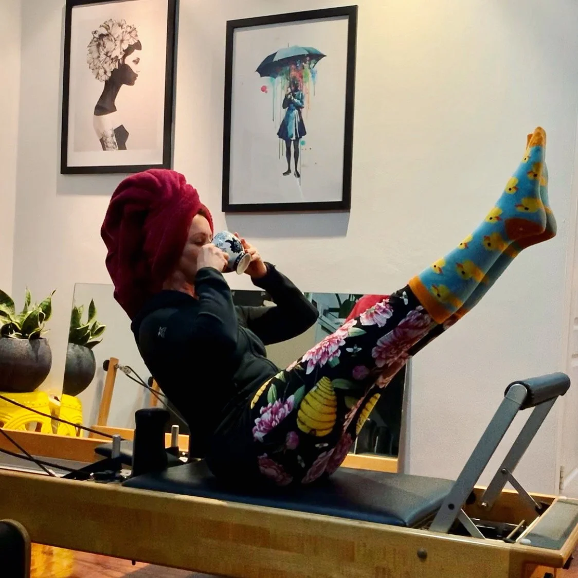 Miss Jo Carey performing a Pilates Teaser on a Pilates Reformer whilst drinking tea