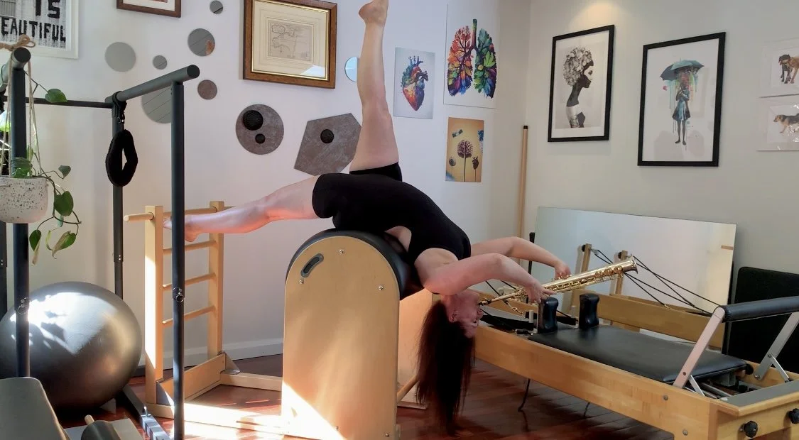 Miss Jo Carey playing Saxophone whilst doing backbend on Pilates Barrel