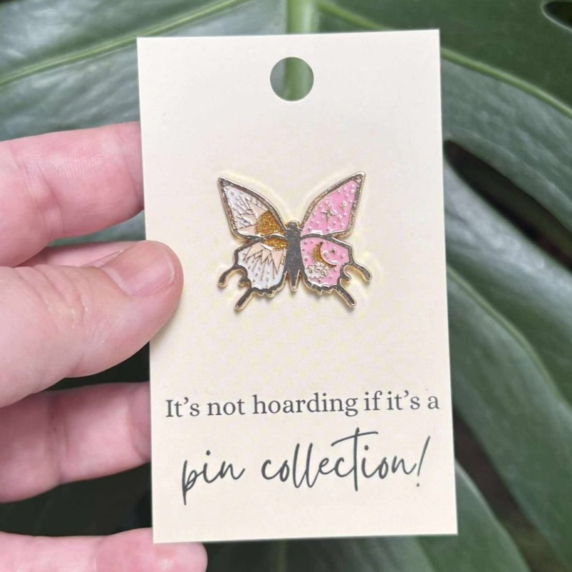 Enamel pin of a butterfly with golden sun and pink starry moon design