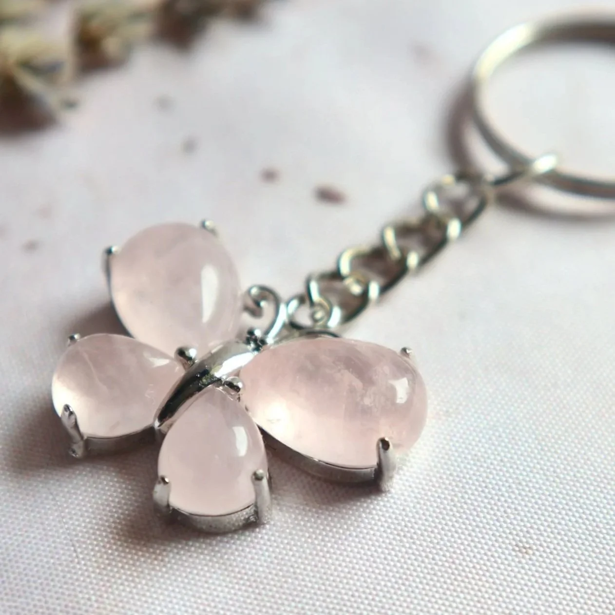Close-up of a butterfly-shaped Rose Quartz keyring with four decorative stones and a silver-tone bail.