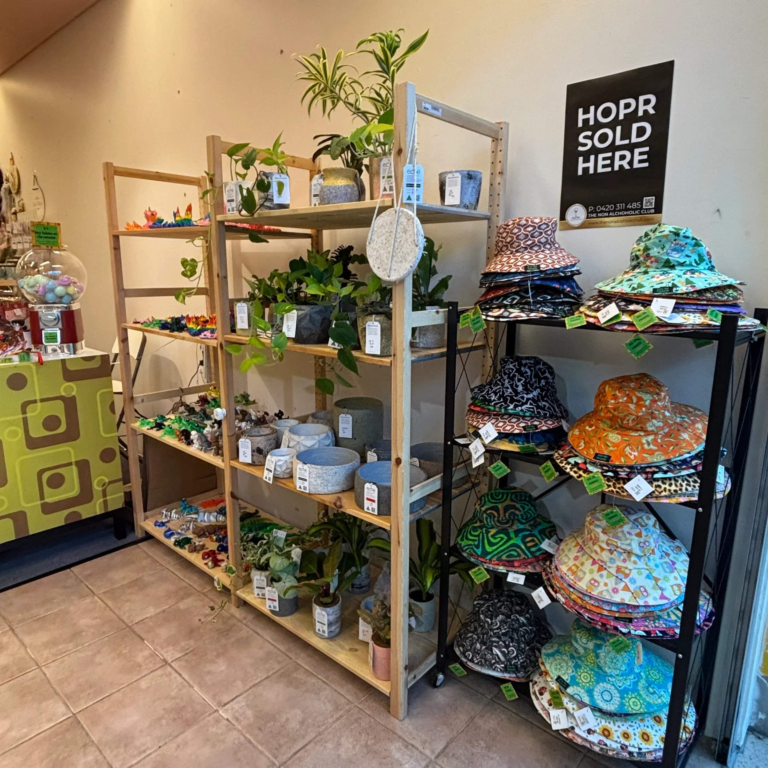 Display of colorful hats with floral and patterned designs on black wire shelves in a store.