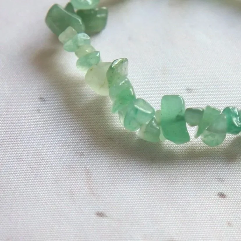 Close-up of the natural green tones and irregular shapes of a Green Aventurine bracelet.