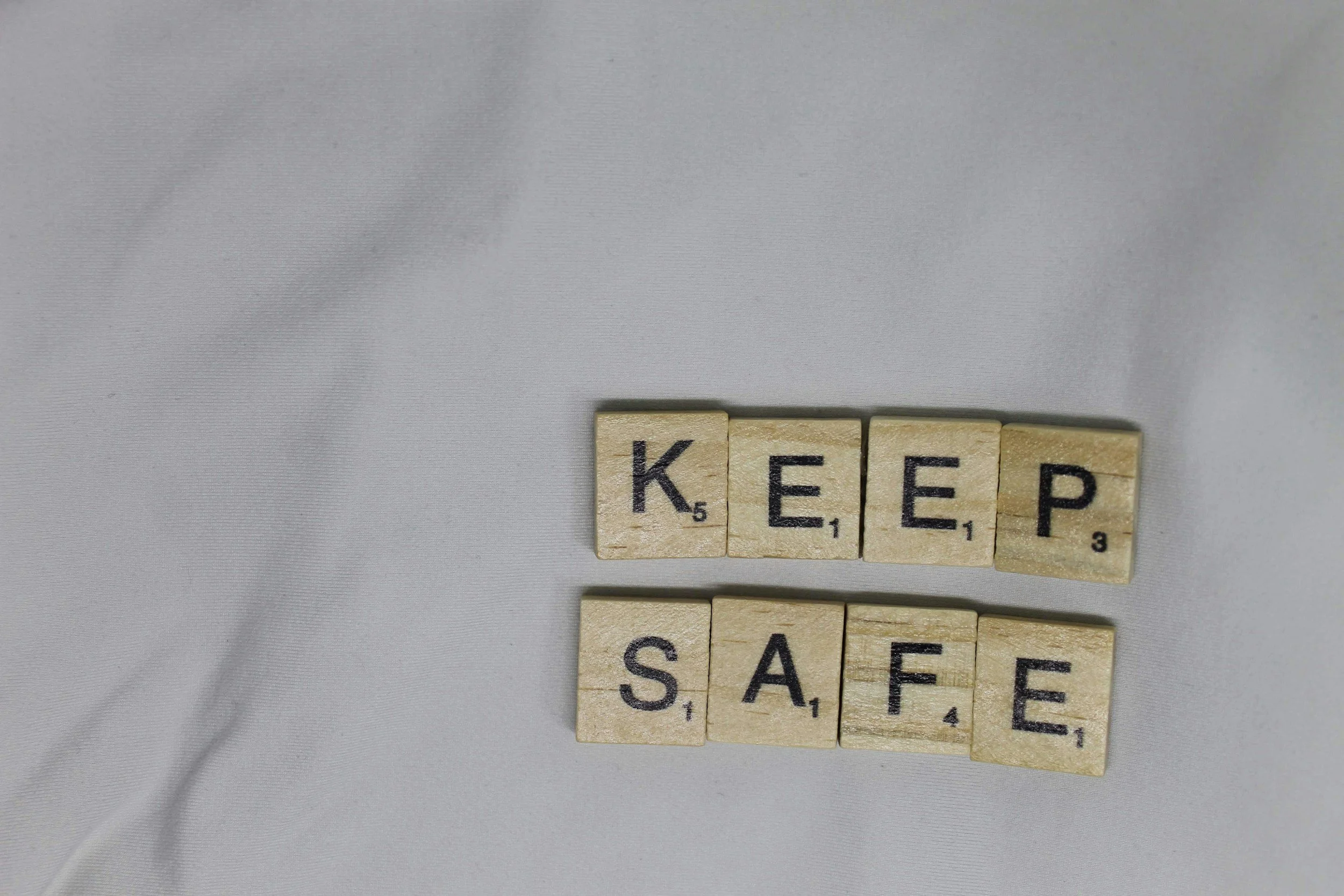 Scrabble tiles spelling out the word 'KEEP' on a light gray fabric background.