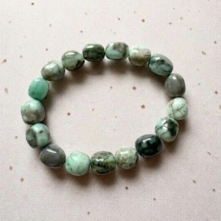 Close up of Emerald gemstone stretch bracelet showing natural green bead variations and polished finish