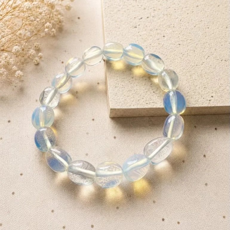 Opalite stretch bracelet featuring smooth round beads with a soft iridescent glow and flashes of blue on a neutral background.