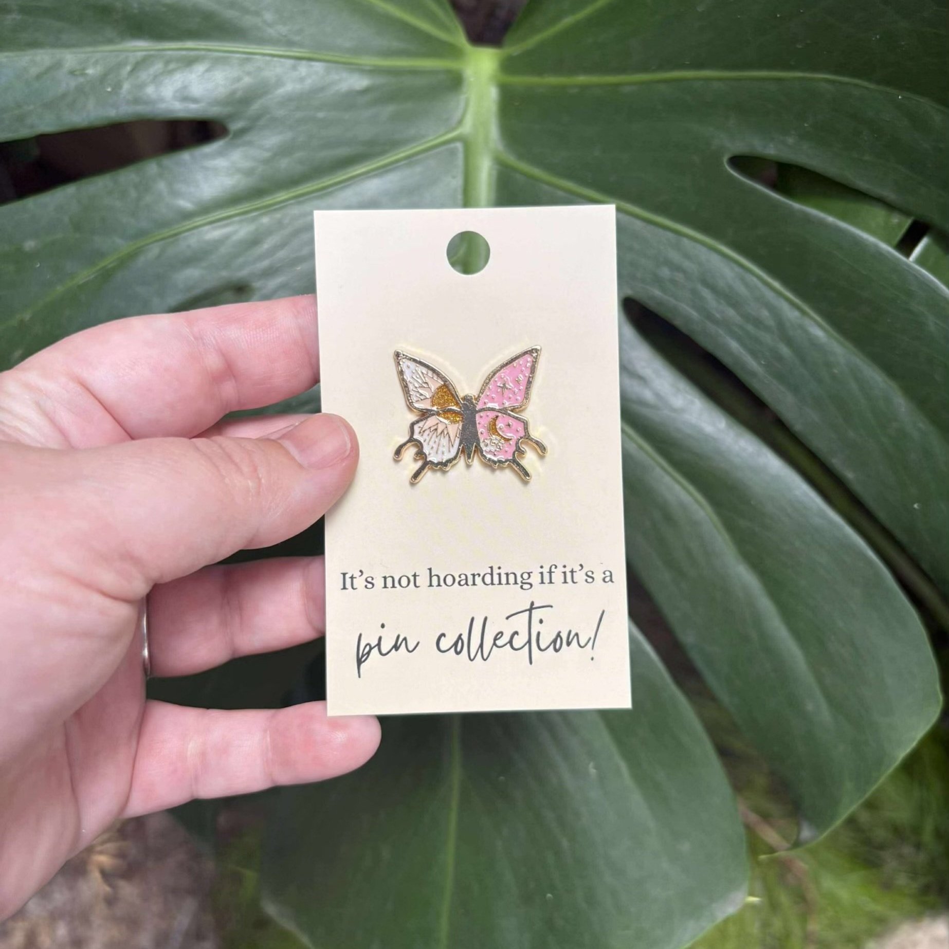 Butterfly enamel pin with sun on one wing and pink moon and stars on the other — celestial nature-themed accessory