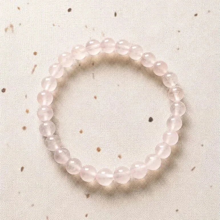 Close up of polished Rose Quartz round bead bracelet with natural blush pink gemstone tones
