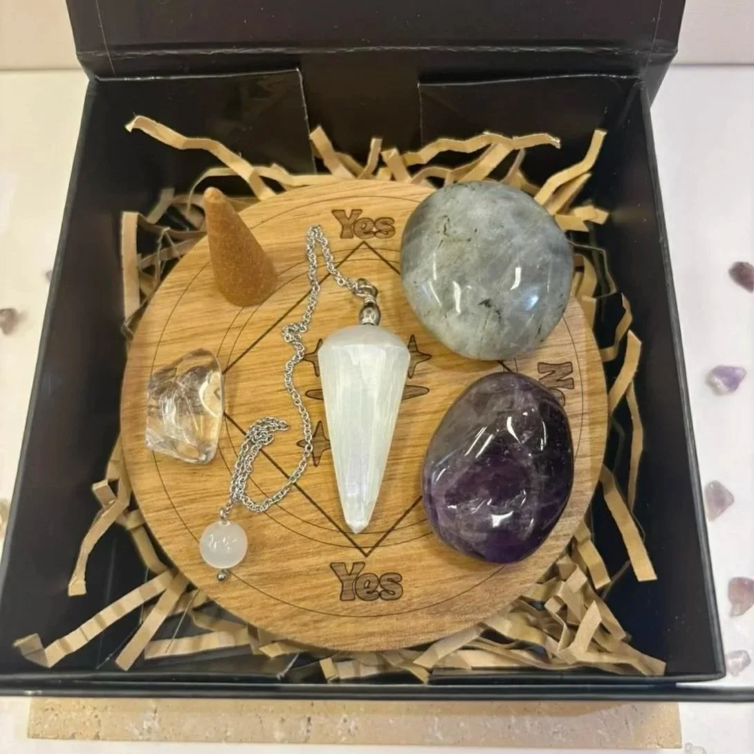 Open magnetic gift box showing crystal set including pendulum, palm stone, Clear Quartz and Amethyst