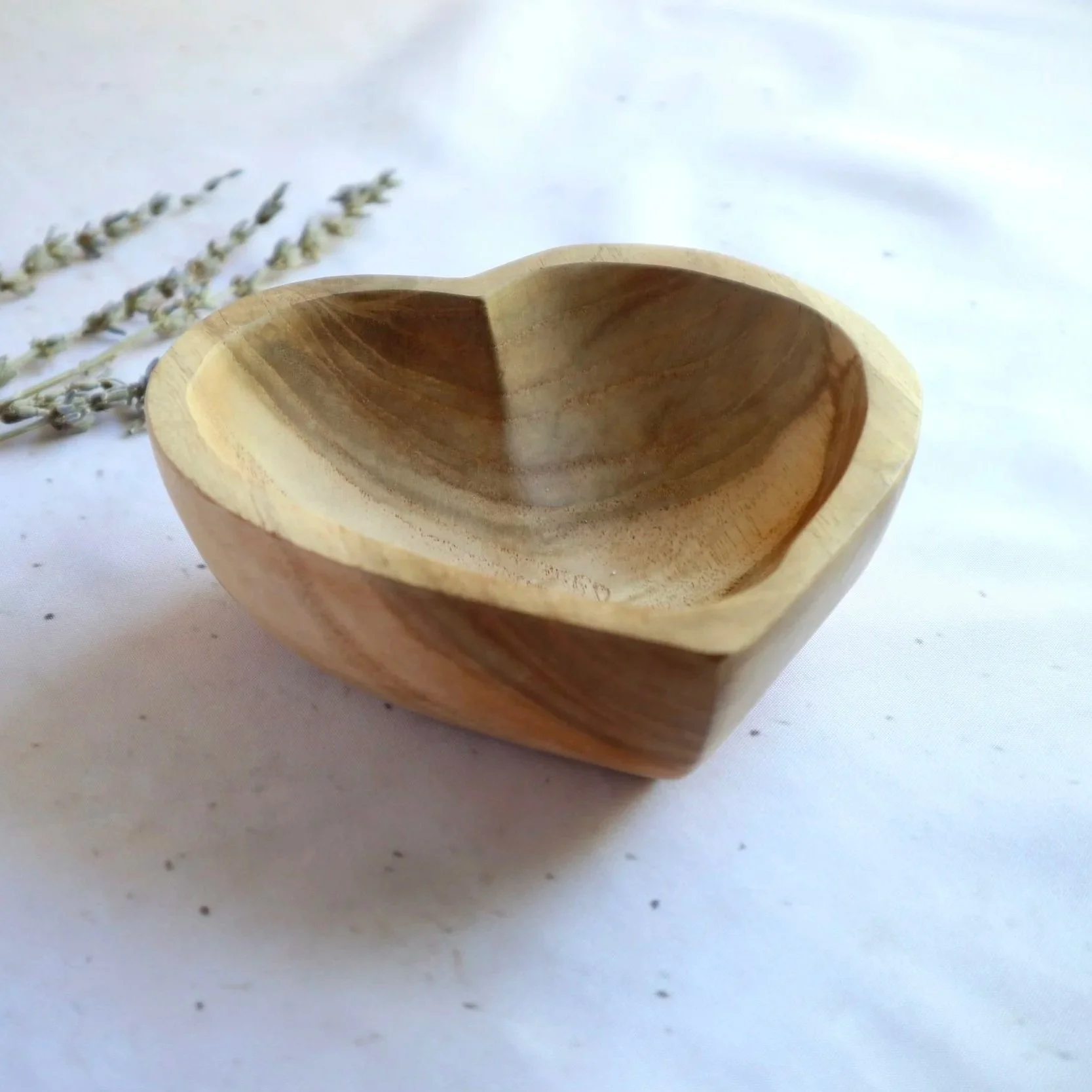 Natural wooden heart bowl displayed on a soft cream background with dried lavender.
