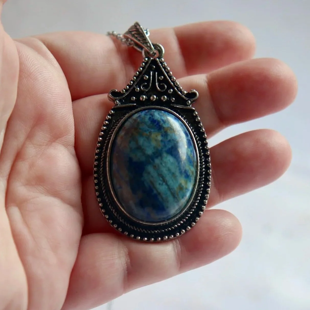 Lapis Lazuli oval necklace shown in hand to demonstrate the approximate pendant size