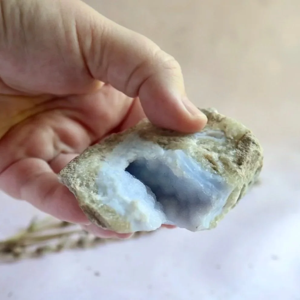 Natural Blue Lace Agate geode showing pale blue crystalline formations inside a rough outer surface