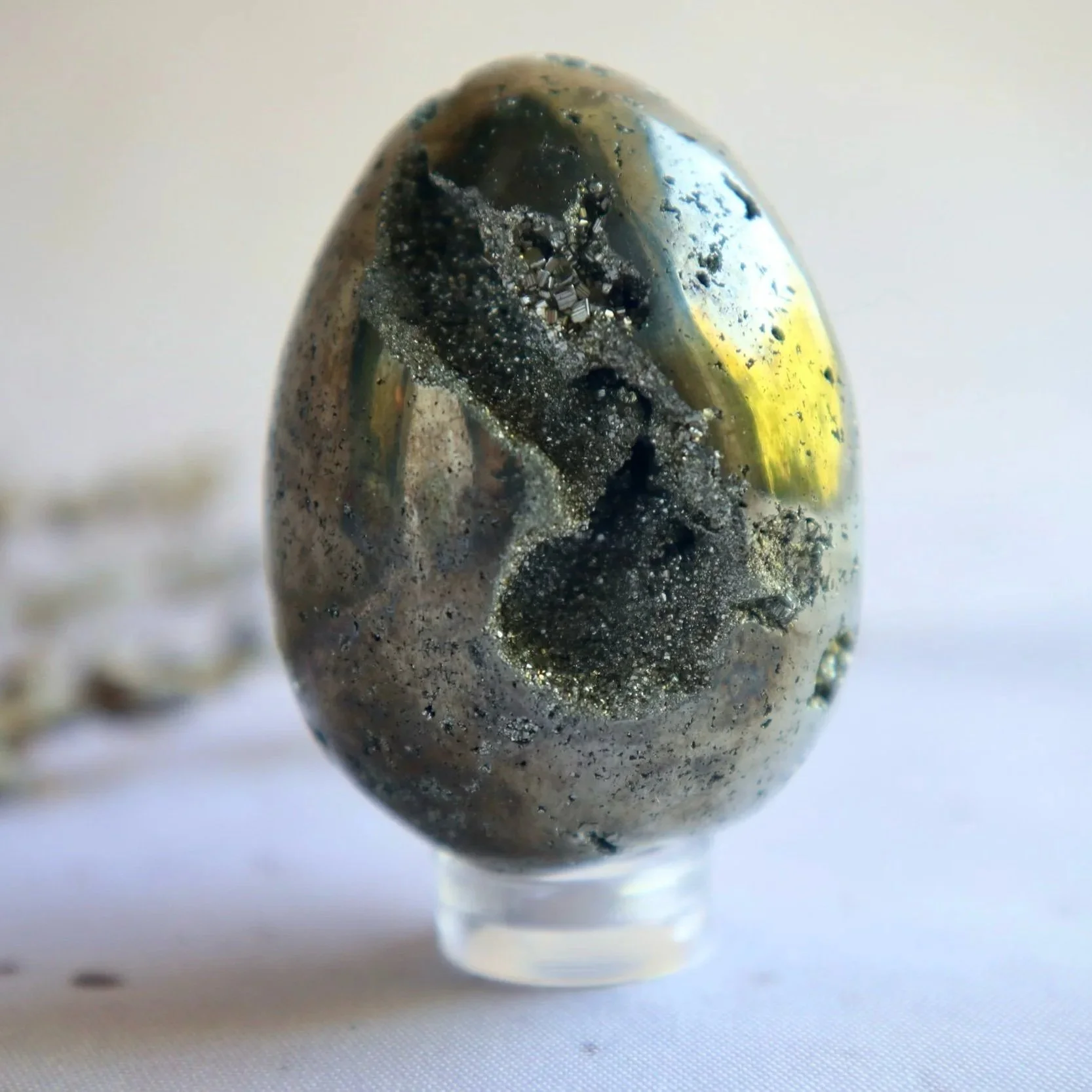 Golden Pyrite crystal egg displayed on a small stand