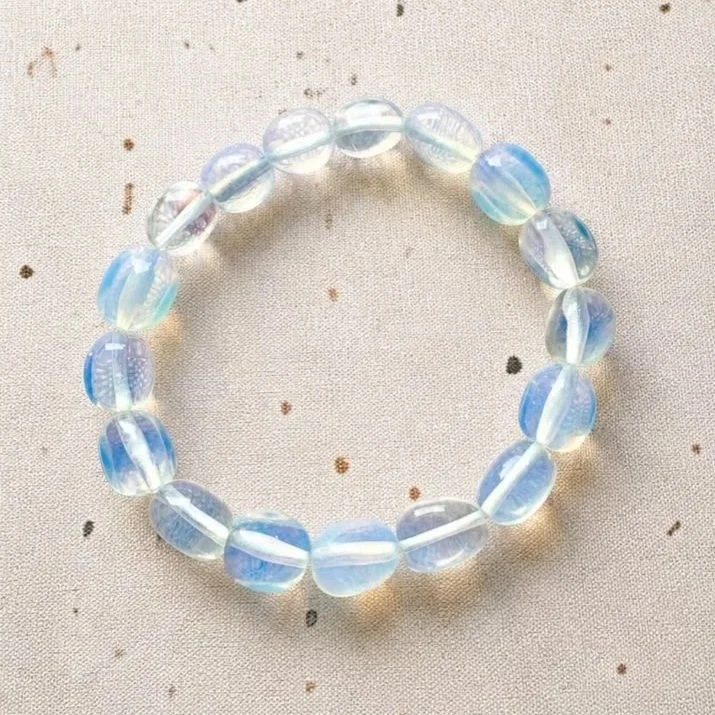 Man-made Opalite beaded bracelet with polished round beads displaying a milky appearance and rainbow-like shimmer.