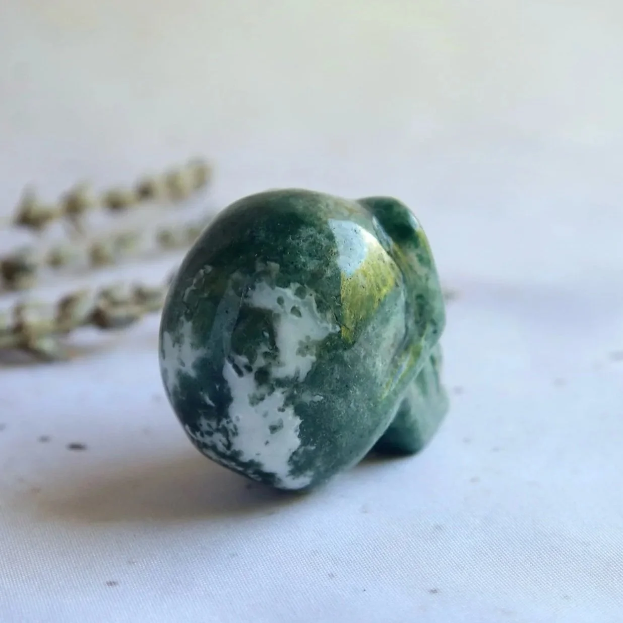 Moss Agate skull carving showing earthy green natural patterns