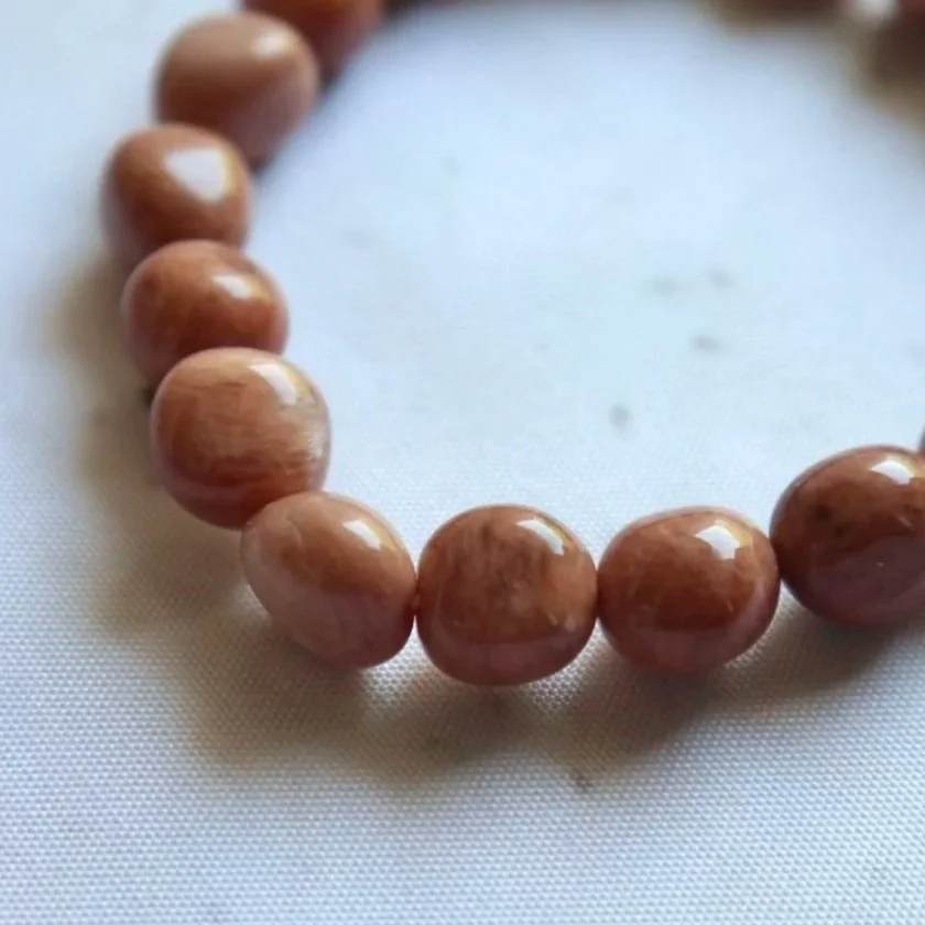 Close-up of polished Orange Moonstone beads in varied orange and peach shades.