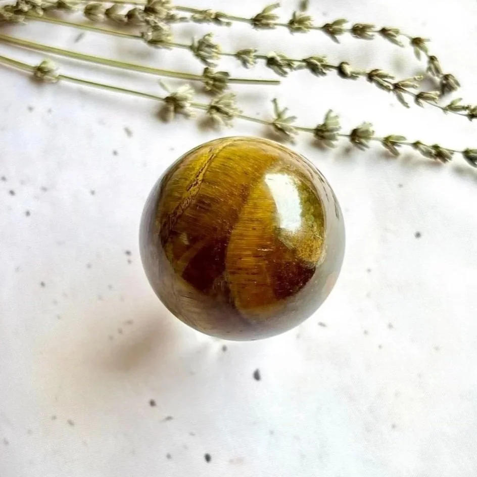 Tiger's Eye crystal sphere displaying golden brown bands and chatoyancy