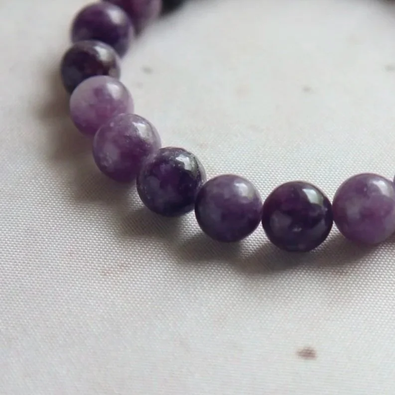 Close-up of polished Lepidolite beads showing natural colour variations.