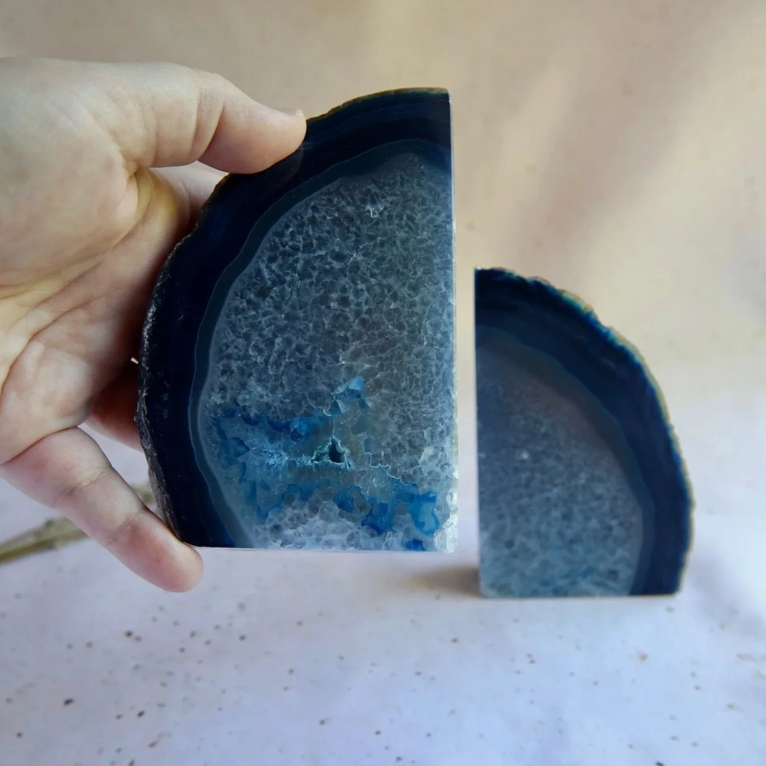 Dyed blue Agate bookends shown with a hand for scale
