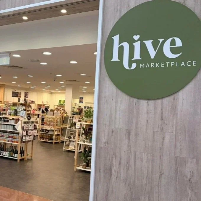 Entrance to Hive Marketplace, a store with various products on display, inside a mall or shopping center.