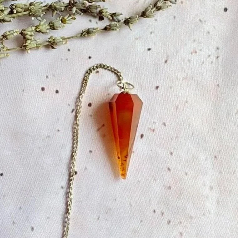 Carnelian pendulum featuring a polished crystal point