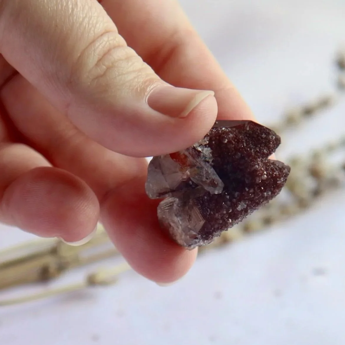 Hematite in Quartz specimen held between fingers to show its petite size and detailed natural texture.
