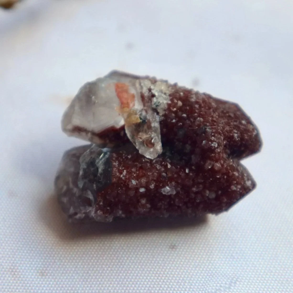 Close-up of the red Hematite-rich surface and contrasting clear Quartz formation on a small mineral specimen.