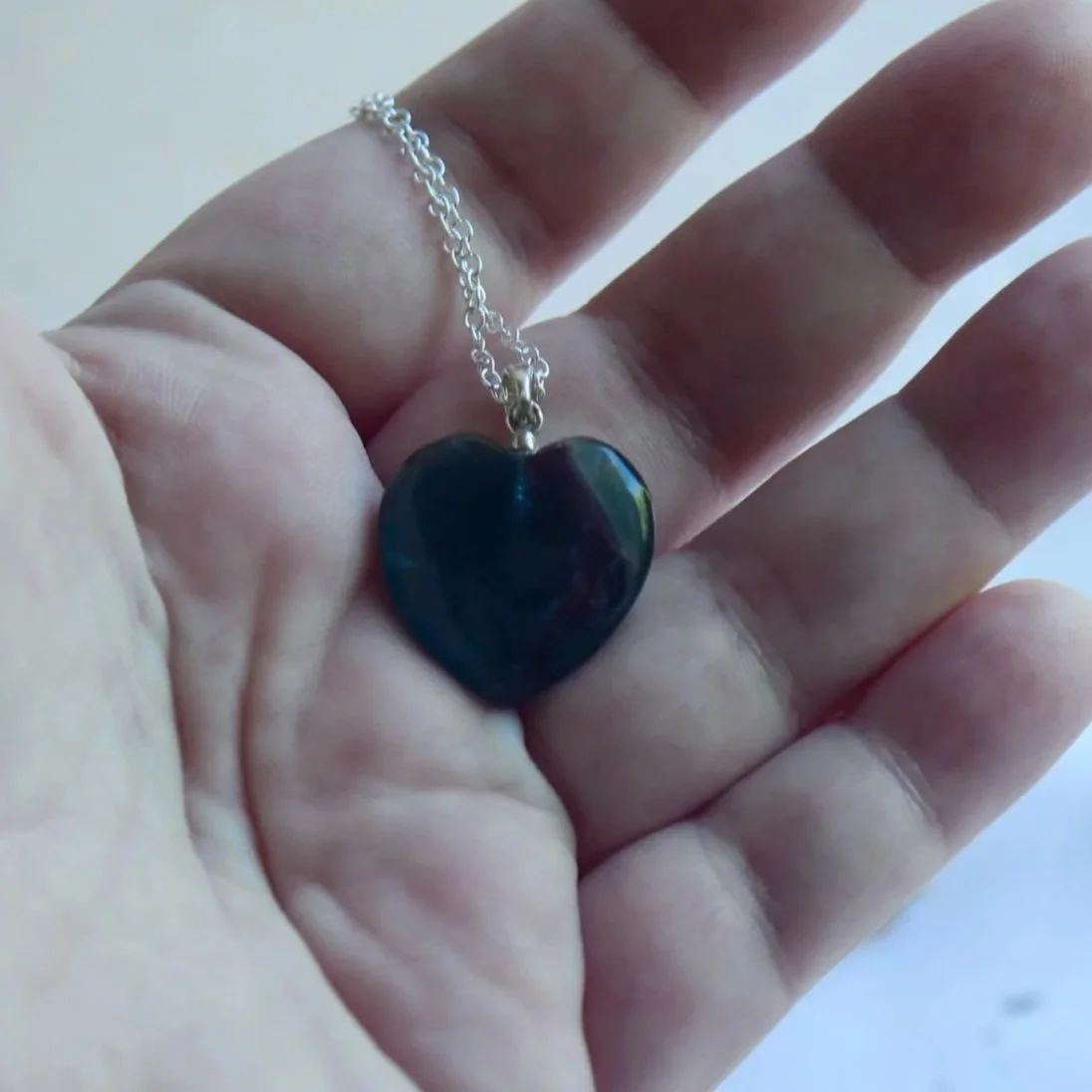 Close-up of a Rainbow Fluorite heart necklace showing the gemstone's natural colour variations.