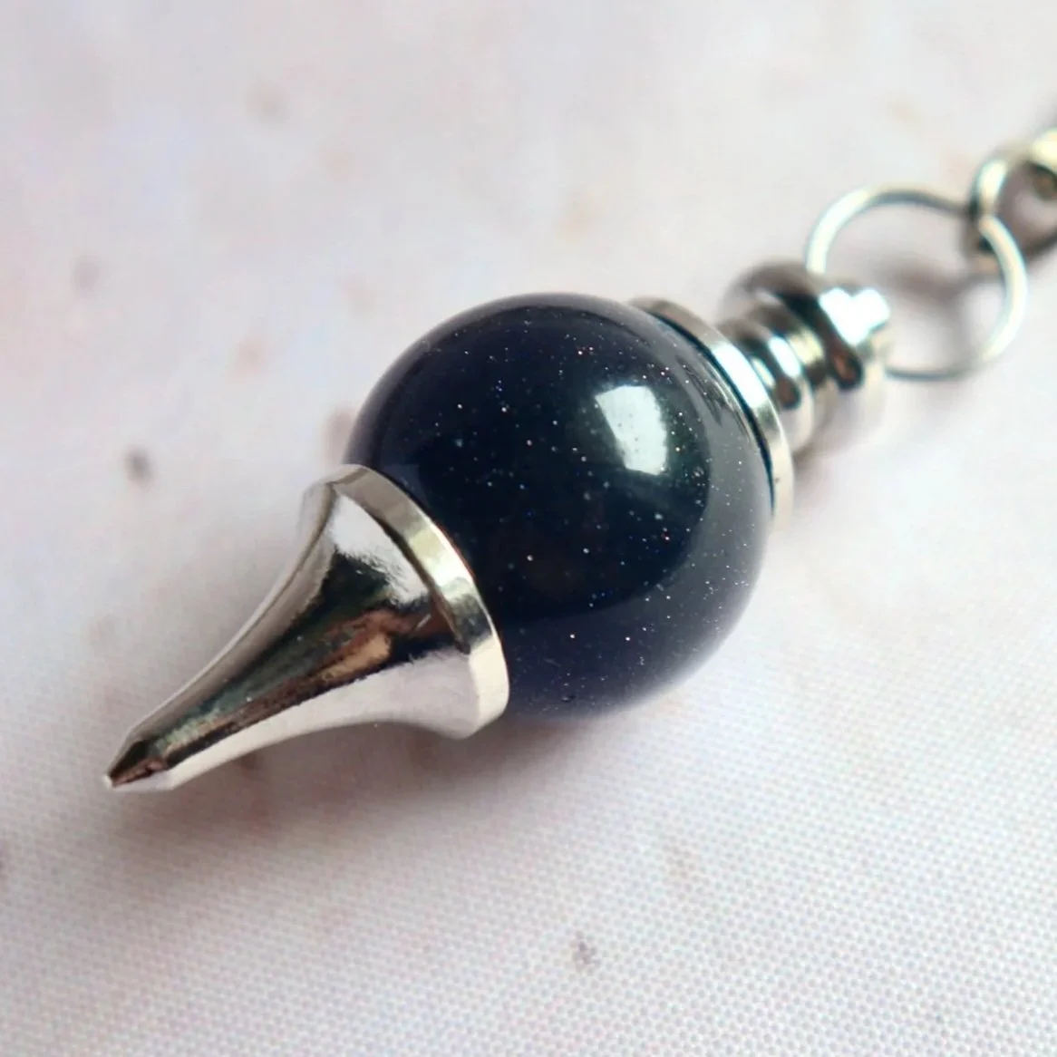 Close-up of a pendulum keyring with a rounded bead and silver-tone metal hardware.