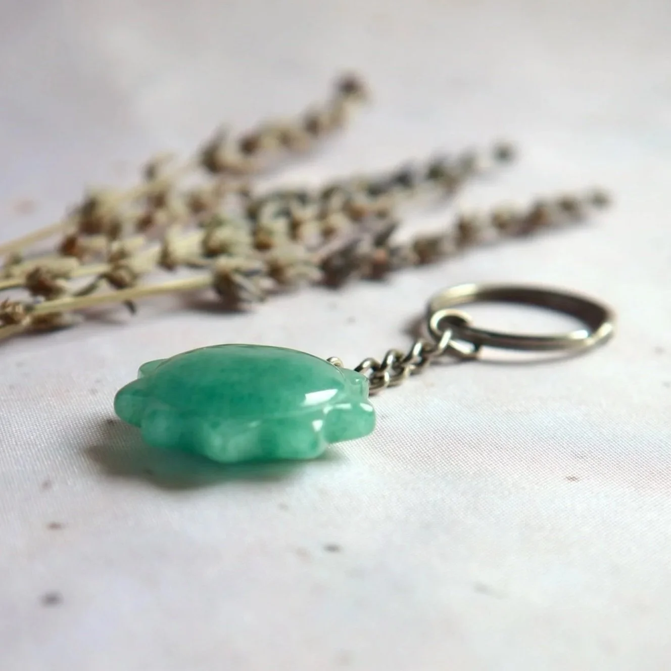 Nature-inspired green gemstone keyring in a multi-pointed sun design.