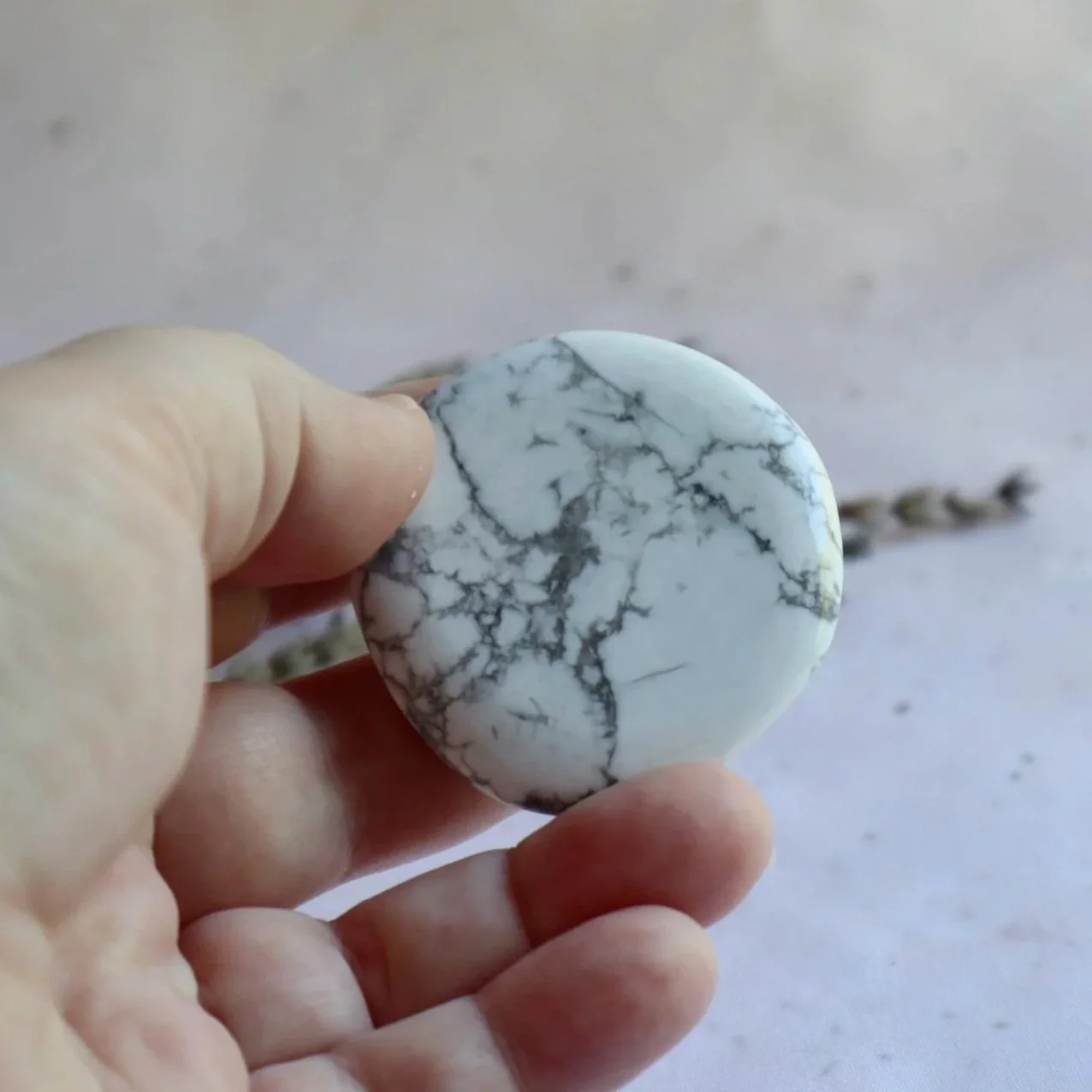 Howlite flat stone shown in hand for size reference