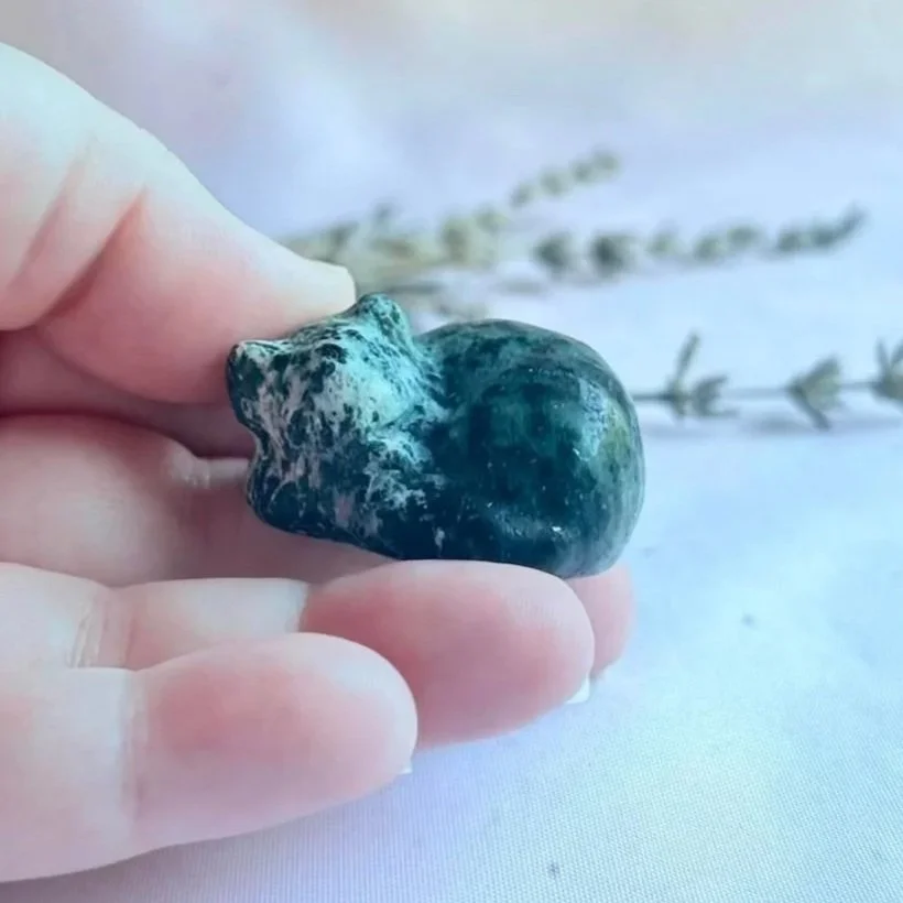 Small Zoisite crystal cat carving in a peaceful sleeping pose with natural green patterns.
