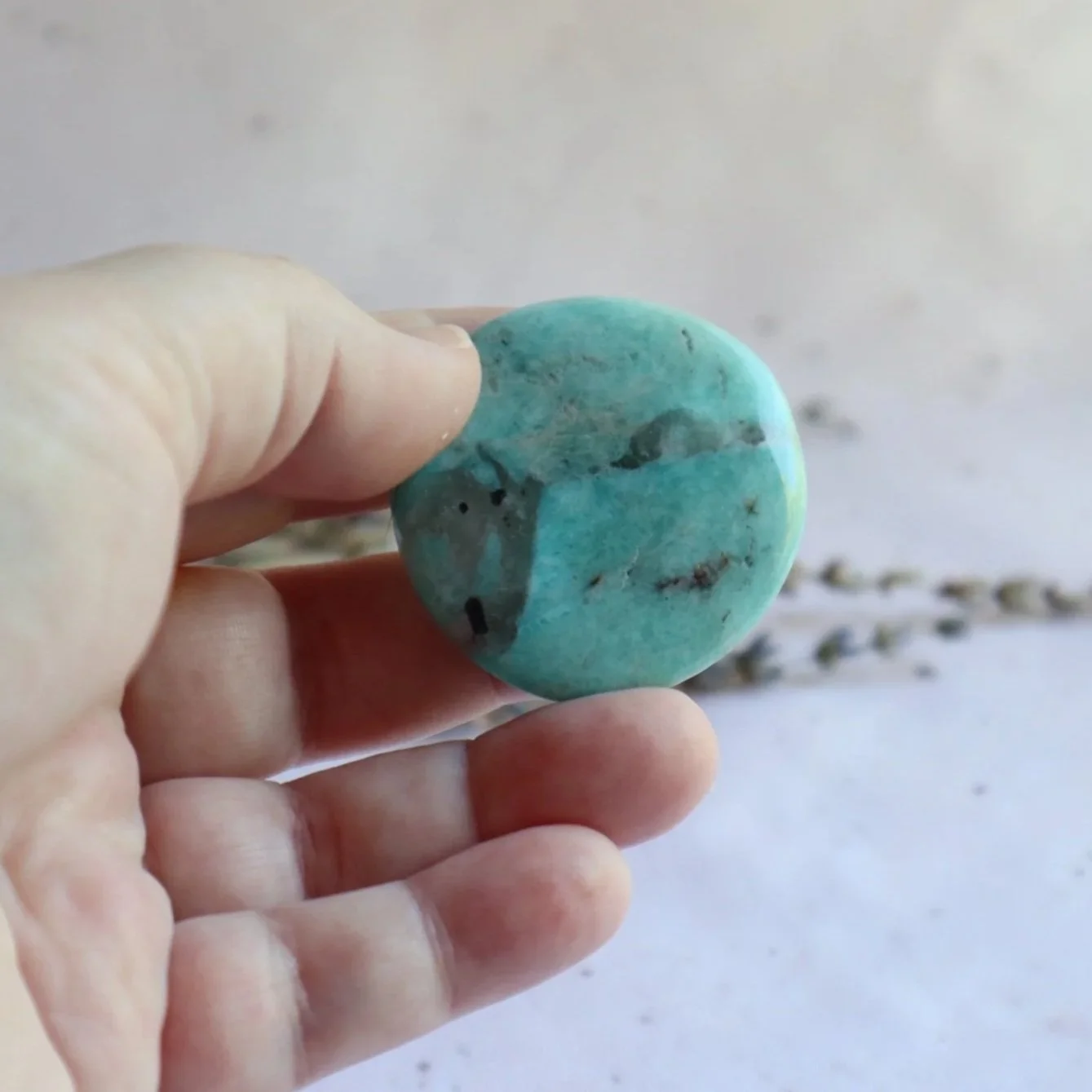 Amazonite flat stone shown with hand for scale