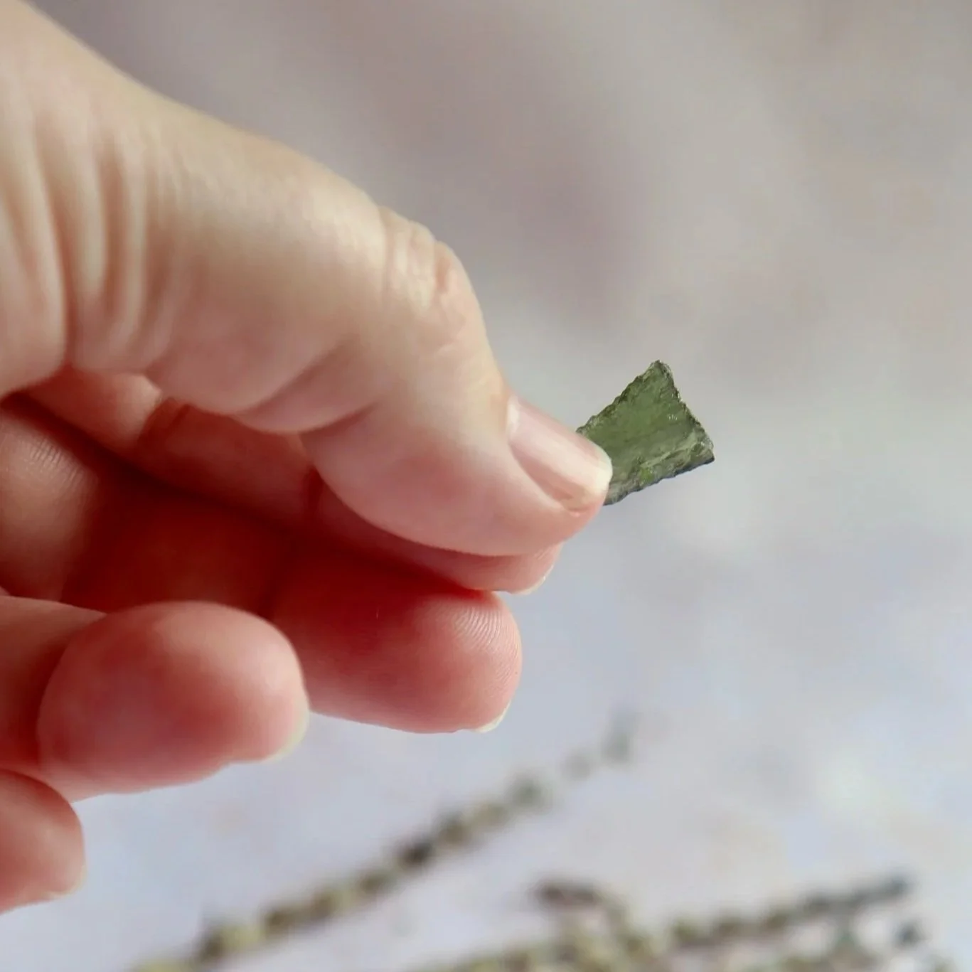 Individual Moldavite specimen showing its natural green colour and irregular form.