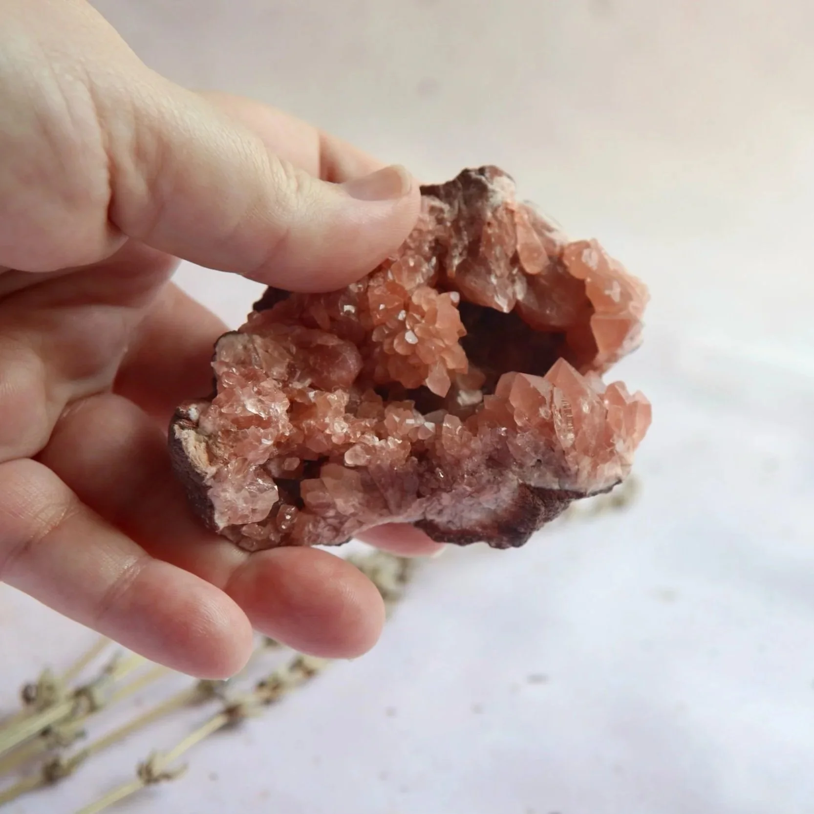 Pink Amethyst crystal cluster held in a hand to show its approximate size and intricate natural formation.