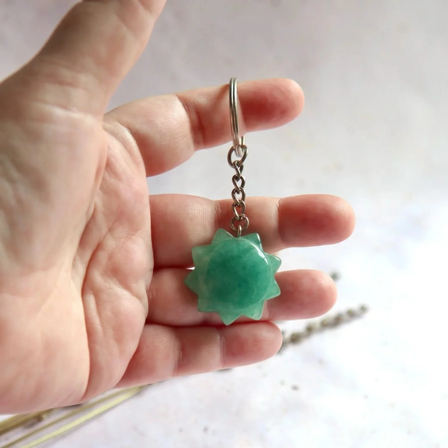Sunburst gemstone keyring featuring a polished green stone with a silver-tone connecting chain and keyring.