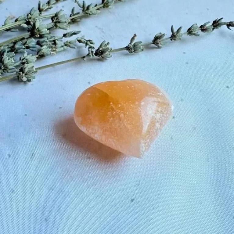 Peach Satin Spar crystal heart associated with peace, emotional healing, and clarity