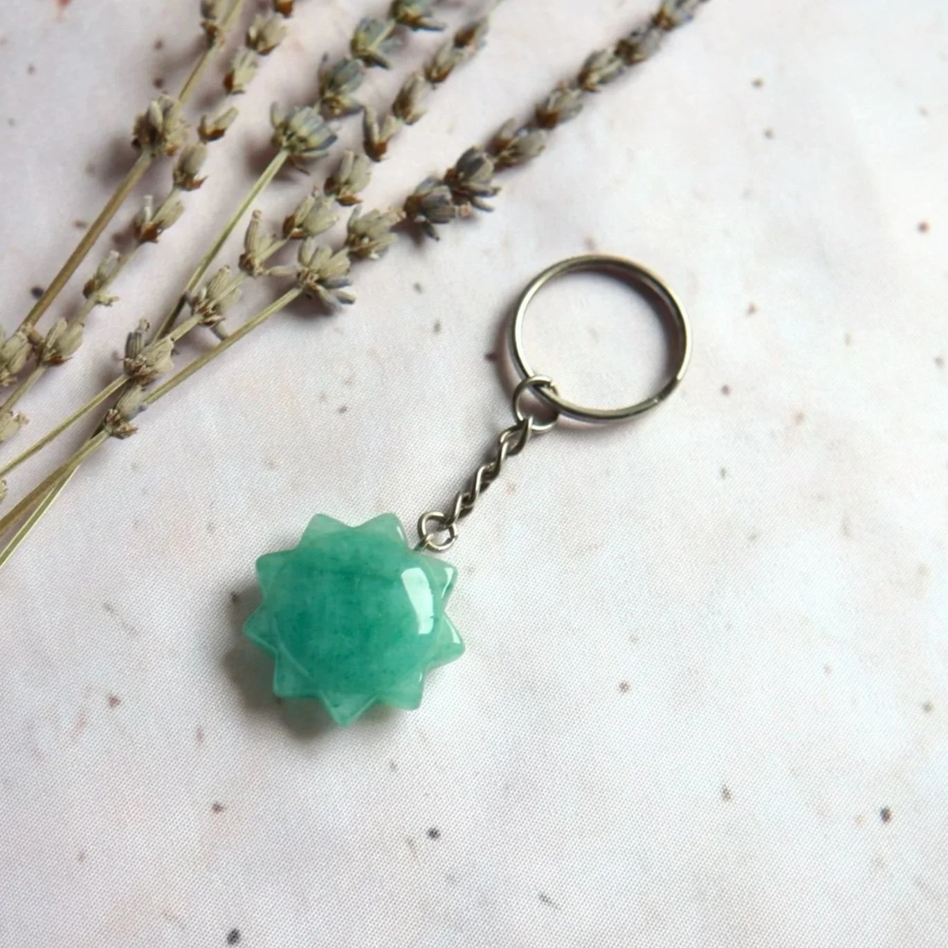 Green sunburst-shaped gemstone keyring with a polished multi-pointed stone and metal keyring attachment.