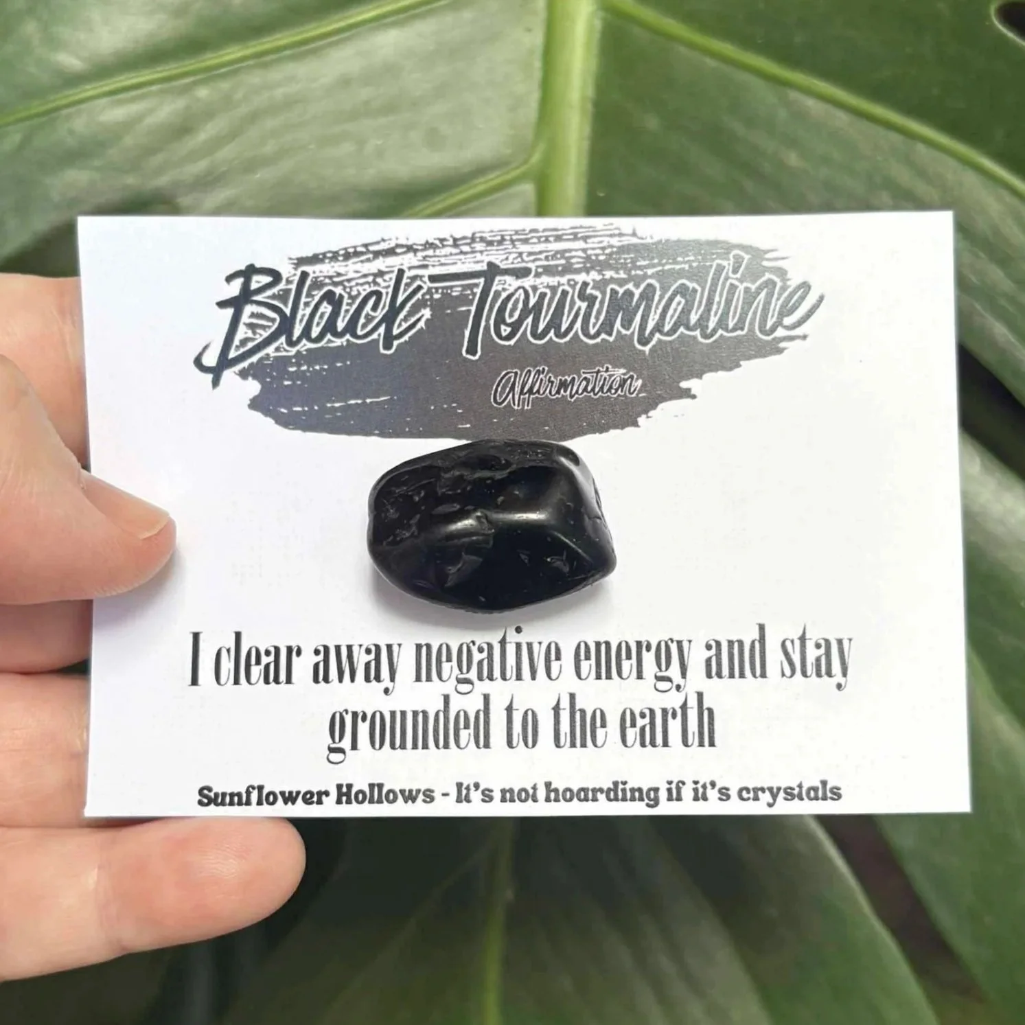 Black Tourmaline crystal paired with affirmation card that reads “I clear away negative energy and stay grounded to the earth