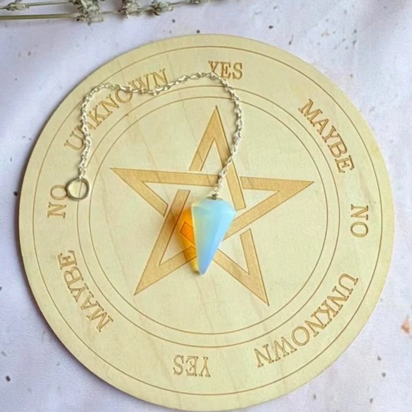 Opalite dowsing pendulum displaying a soft milky glow with blue flashes