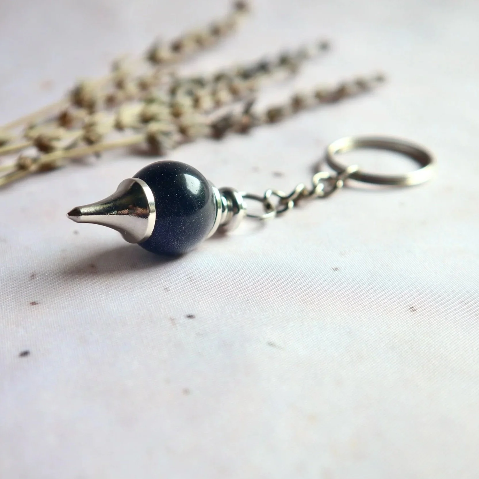 Pendulum-style keyring measuring approximately 40 mm tall, with a rounded bead and pointed metal fitting.