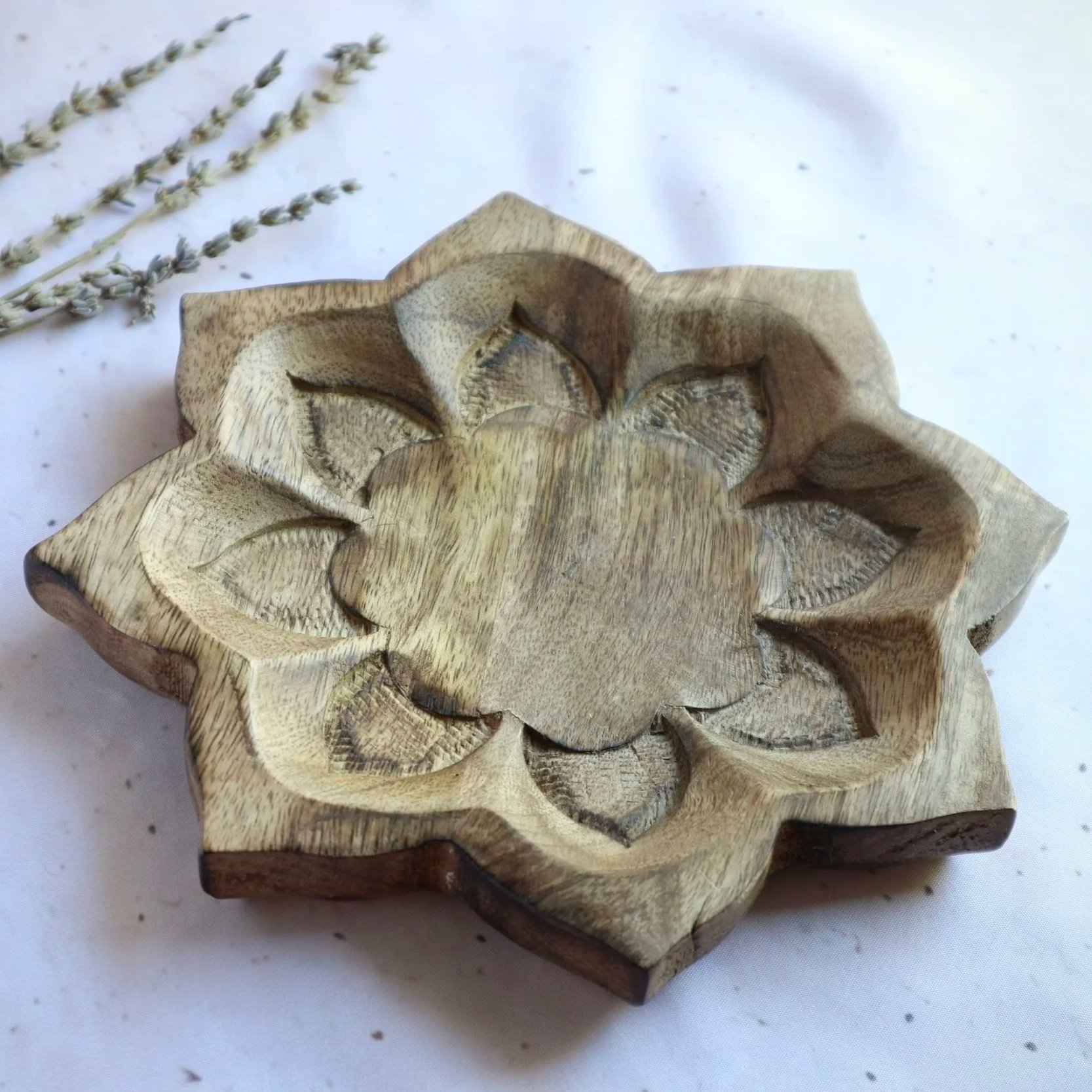 Natural timber lotus tray displayed on a cream fabric background with dried lavender.