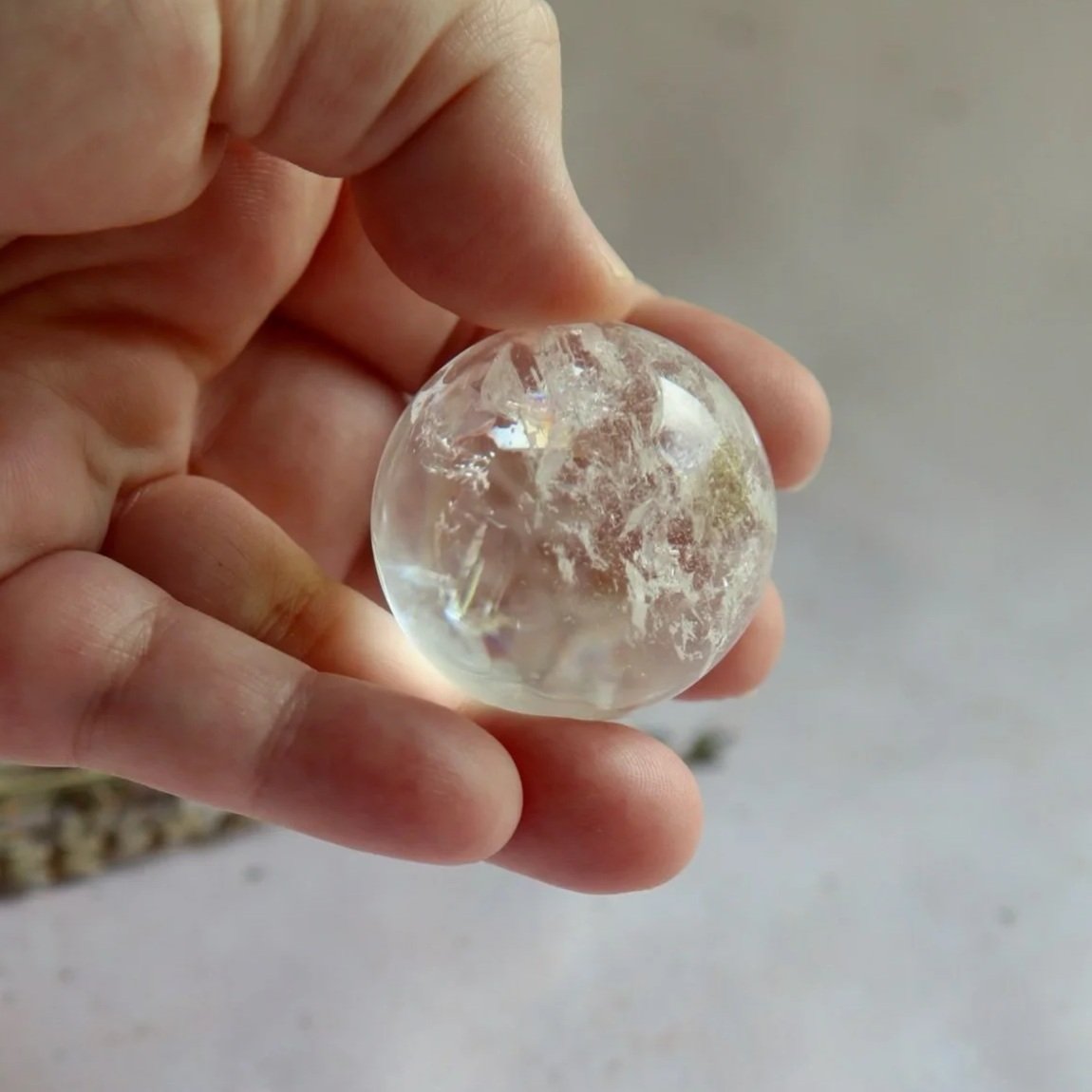 Natural Clear Quartz sphere displaying clear crystal structure and unique internal features