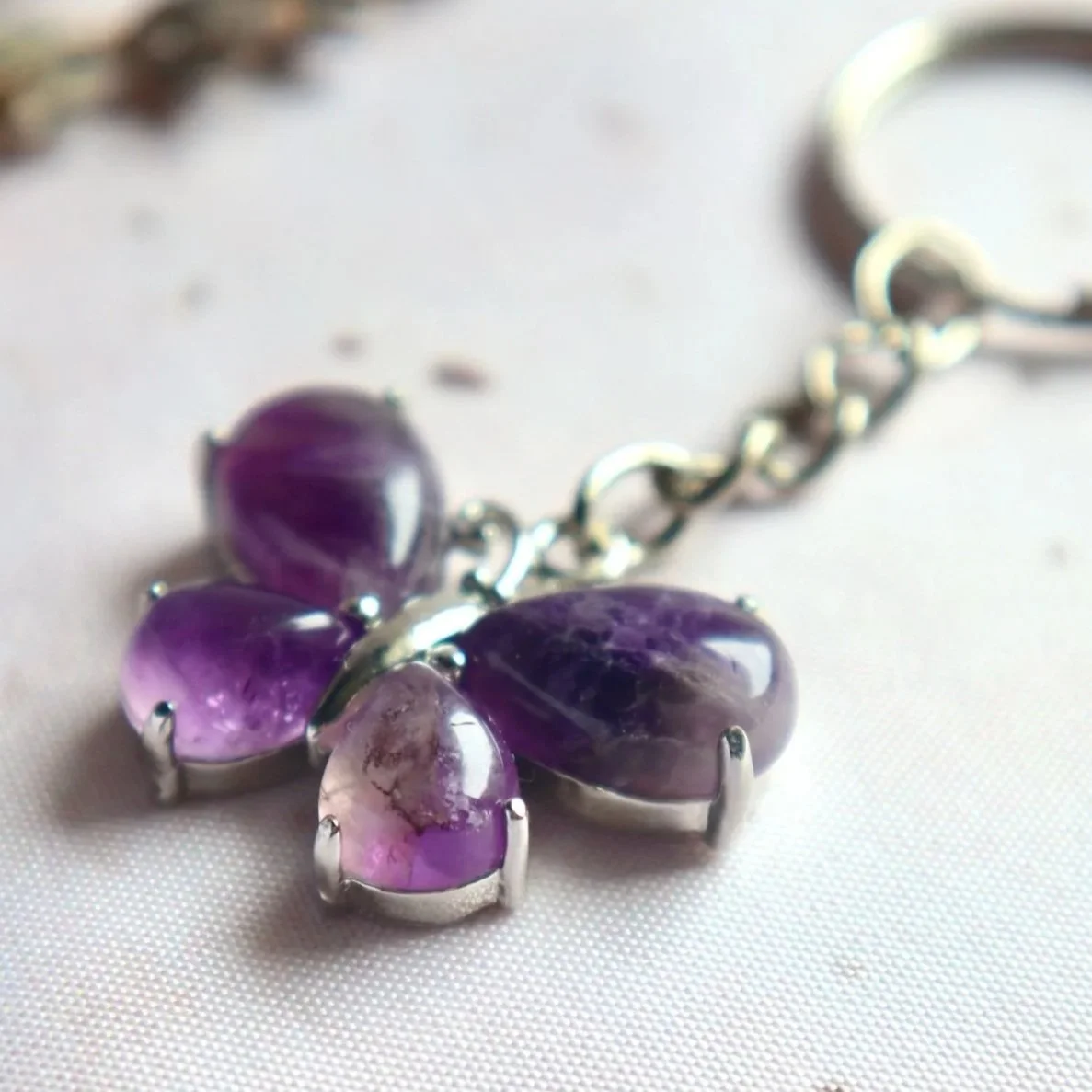 Close-up of a butterfly-shaped Amethyst keyring with four decorative stones and a silver-tone bail.