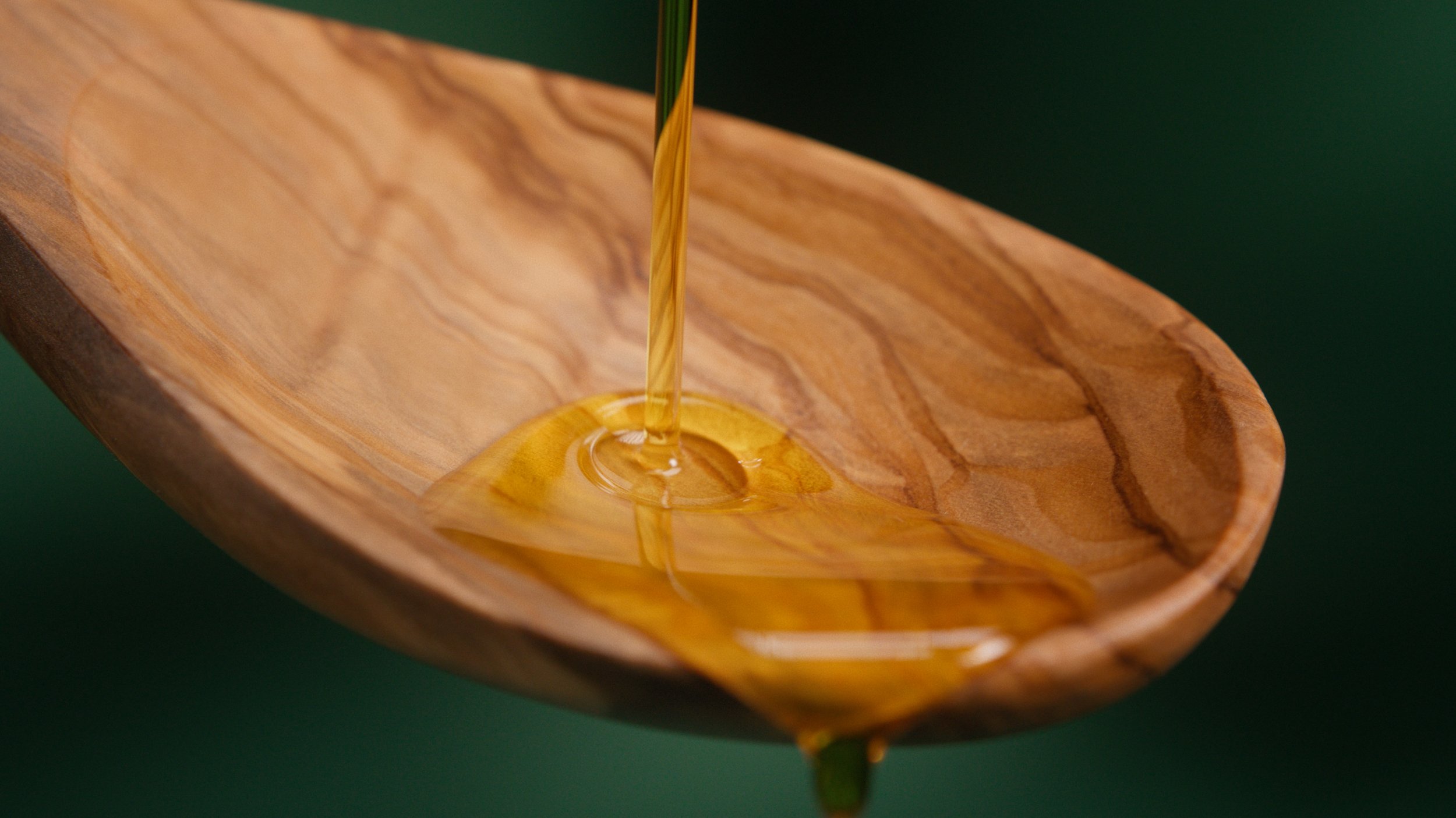 Rapsöl läuft über einen Holzlöffel