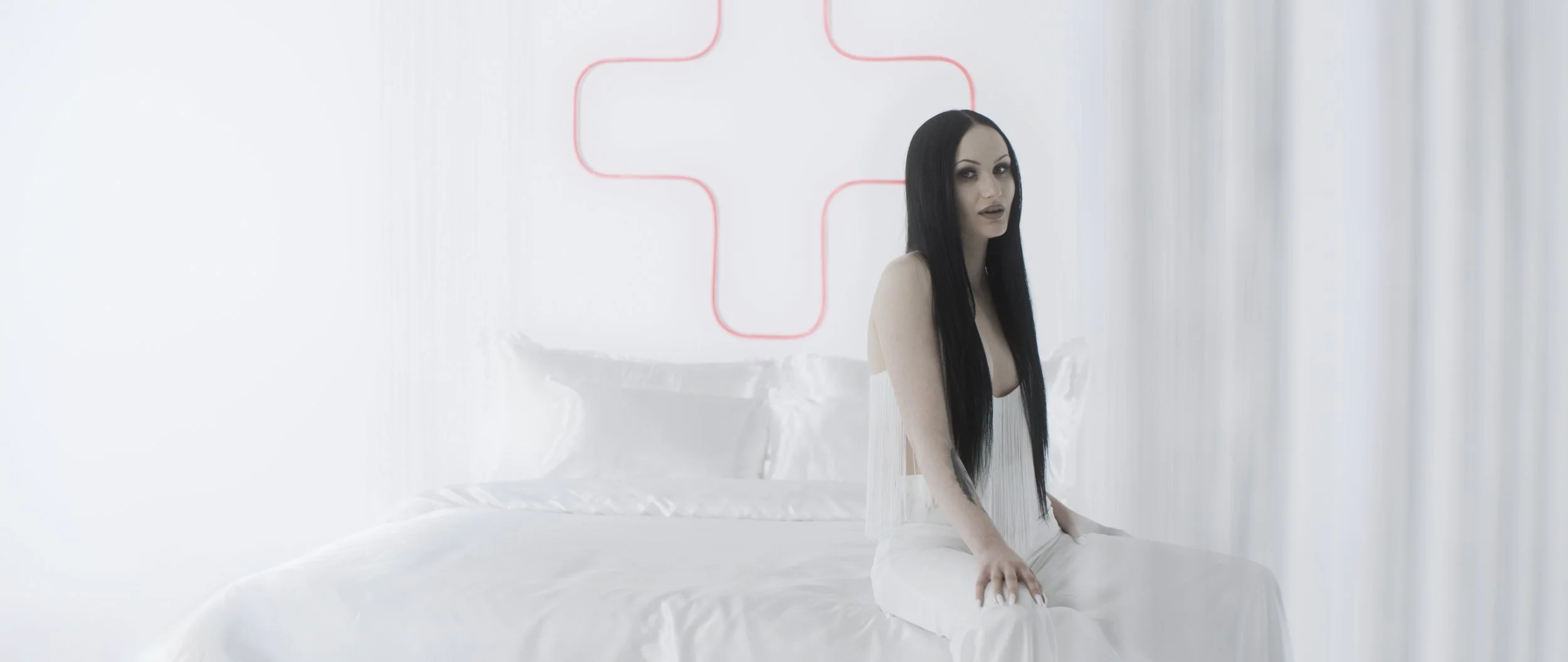 woman dressed in white sitting on a white bed